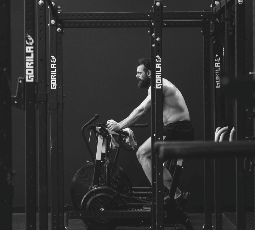 Athlete riding a Concept2 BikeErg with a weighted vest during a cardio-focused WLD training session.