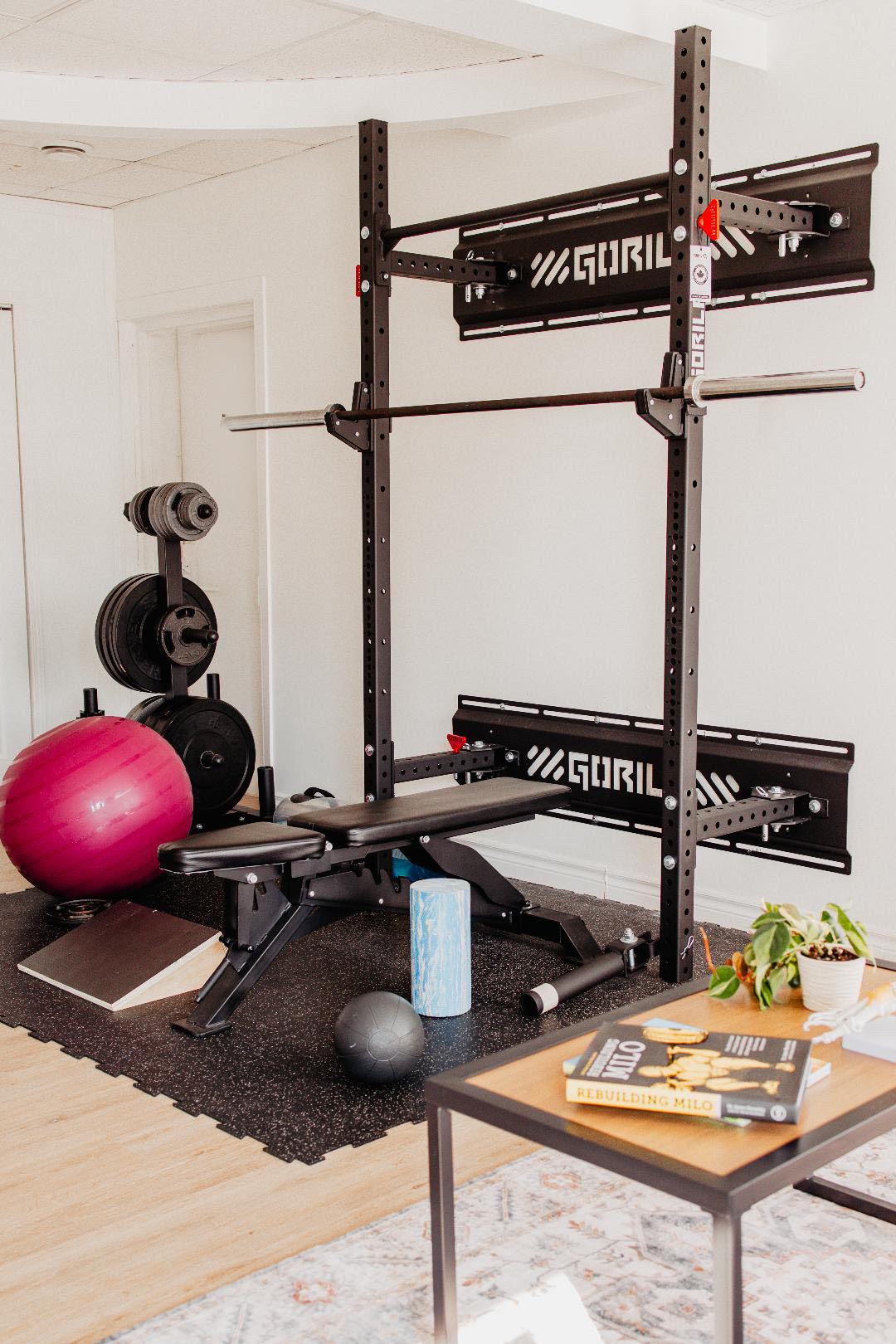 Home gym setup featuring a Gorila power rack, adjustable bench, barbell, and weight plates in a modern living space, showcasing durable Canadian-made fitness equipment.