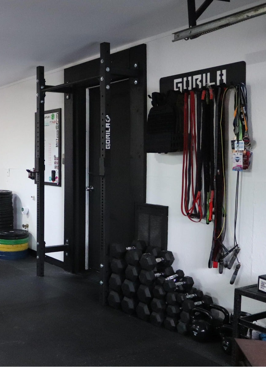 Small home gym with essential racks, barbell and plates for training on a budget