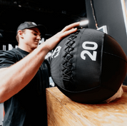 Person holding a 20-pound medicine ball in a gym setting