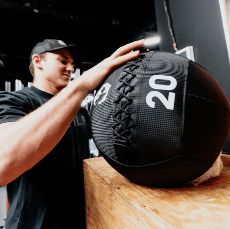 Person holding a 20-pound medicine ball in a gym setting