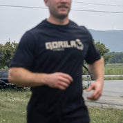 Man wearing a black and tan Gorilla Fitness t-shirt outdoors with a blurred background - blurry effect
