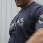 Man wearing a navy blue Gorila Fitness t-shirt with a tan logo, standing against a plain background