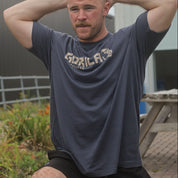 Man wearing a 'Gorilla' t-shirt outdoors with a building in the background while working out.