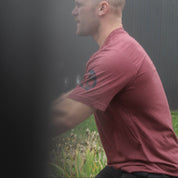 Man in a red shirt standing in a foggy outdoor setting, training outside a Crossfit gym