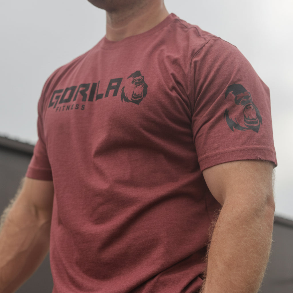 Man wearing a red t-shirt with 'Gorila Fitness' text on it, standing against a plain background