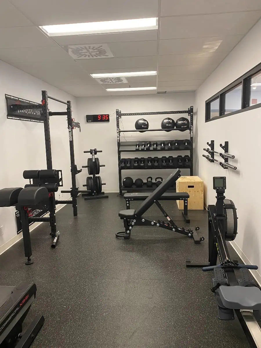 Compact gym setup featuring a sleek, modern design with black Gorila Fitness equipment, including a power rack, adjustable bench, dumbbells, kettlebells, and wall-mounted storage, perfect for maximizing small commercial or home gym spaces.