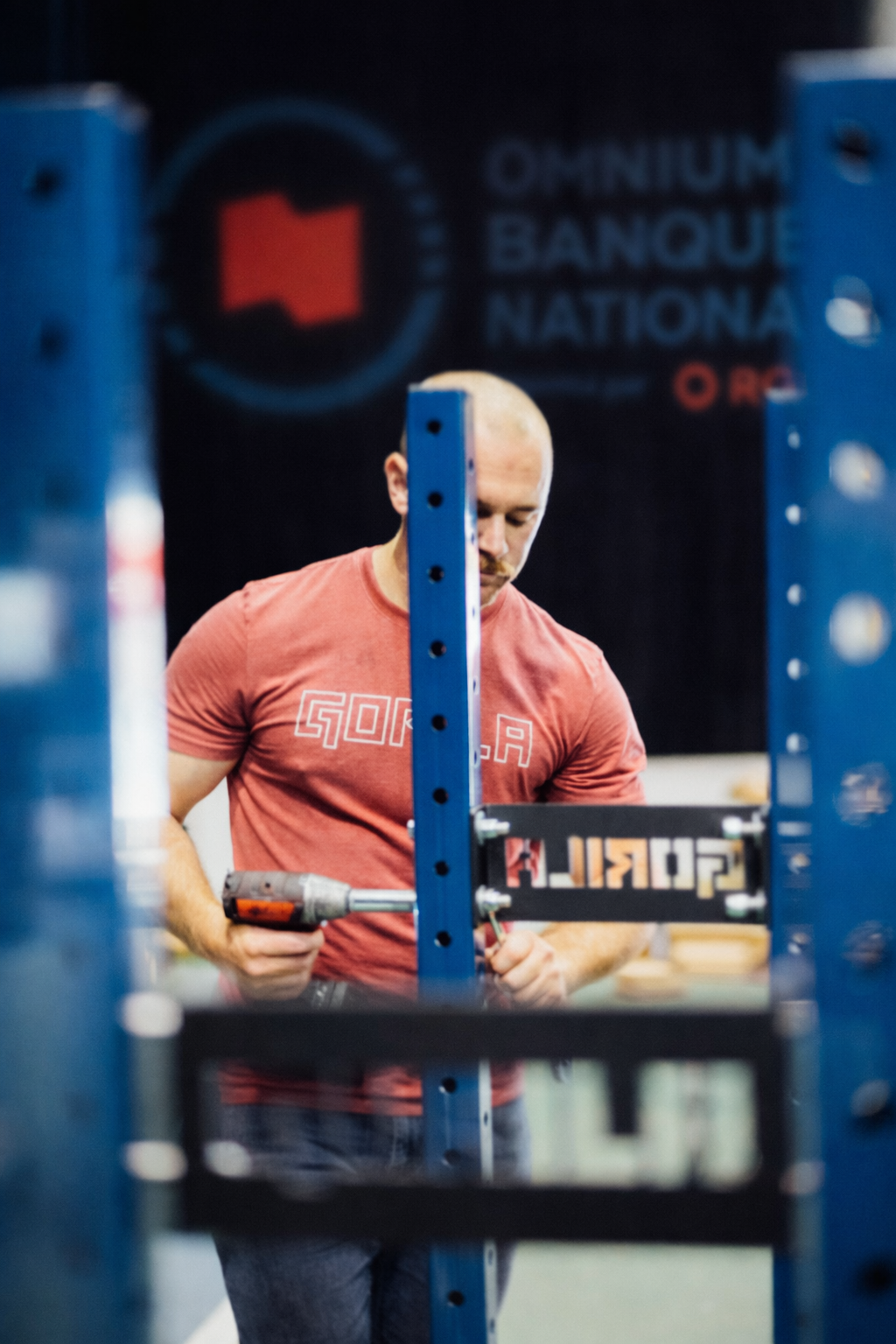 Person installing a Gorila Fitness storage rack with a blurred background featuring 'Omnium Banque Nationale' logo.