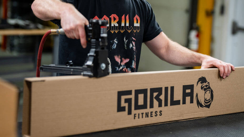 Man repackaging a refurbished Gorilla Fitness product in a warehouse setting