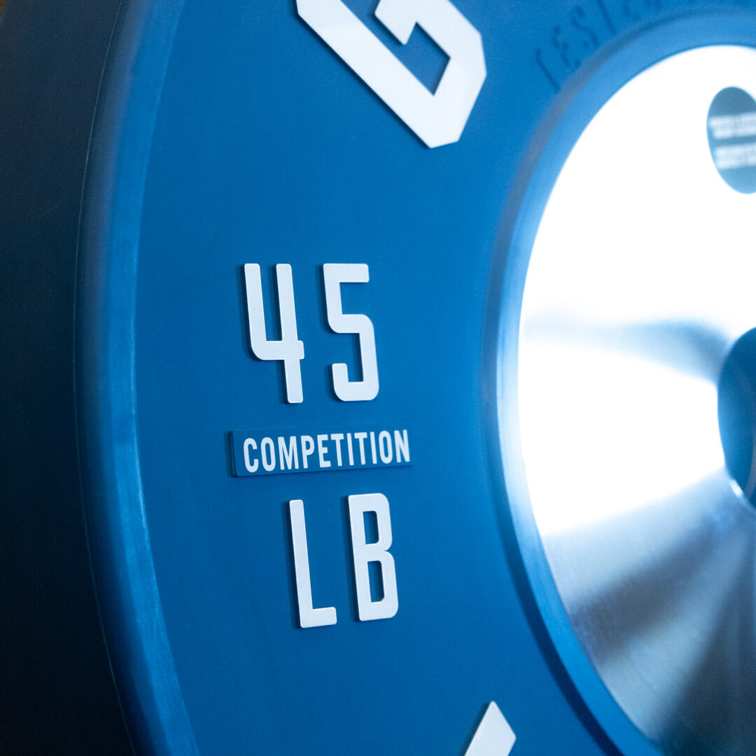 Stack of blue 45 lb Gorila LB Competition Plates under direct lighting, close-up on the embossed details of the plate