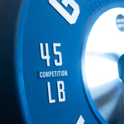 Stack of blue 45 lb Gorila LB Competition Plates under direct lighting, close-up on the embossed details of the plate