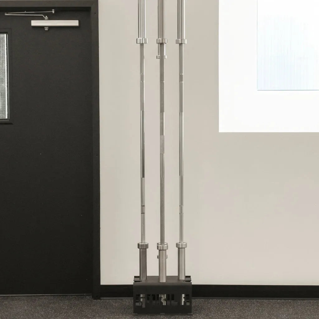 Full-size Olympic barbells stored vertically in the Gorila 5 Bar Holder against a light gym wall, showing stable upright organization and efficient use of space.