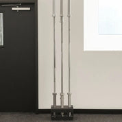 Full-size Olympic barbells stored vertically in the Gorila 5 Bar Holder against a light gym wall, showing stable upright organization and efficient use of space.