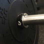 Gorila Aluminium Barbell Collars mounted on a barbell inside a training setup, surrounded by black rubber bumper plates, showcasing a professional gym-ready configuration.