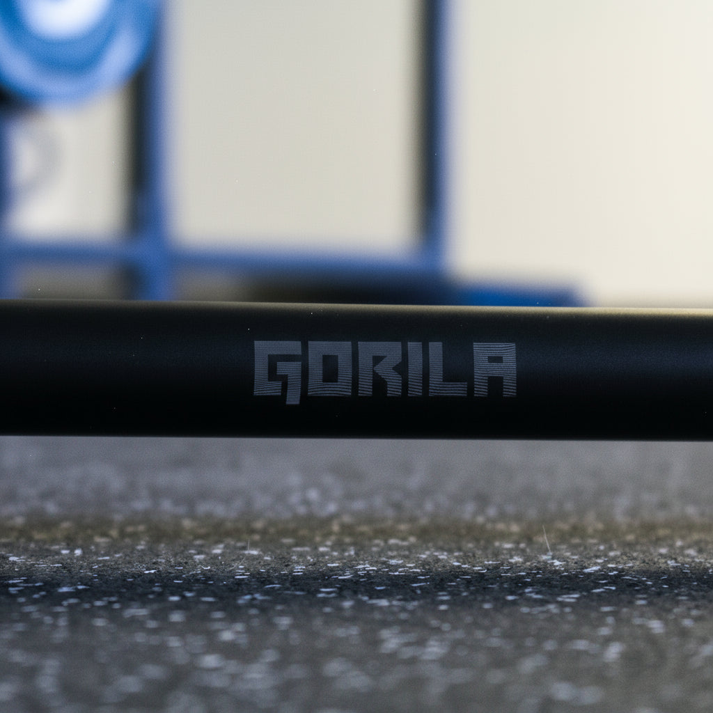 Close-up of Gorila Bar Teflon logo – matte black barbell with dust-resistant PTFE coating, precision machining, and 190,000 PSI tensile strength.