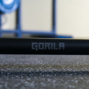 Close-up of Gorila Bar Teflon logo – matte black barbell with dust-resistant PTFE coating, precision machining, and 190,000 PSI tensile strength.