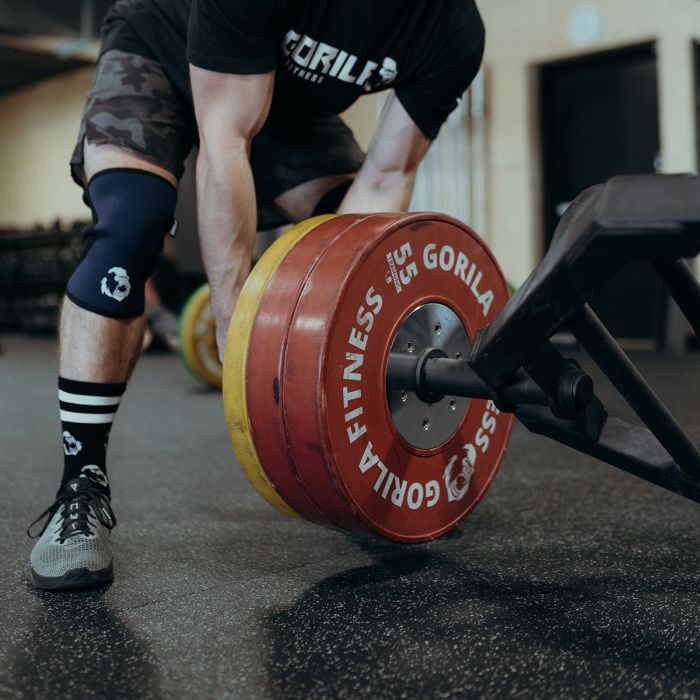 Athlete setting up for a trap bar lift using the Gorila Blastoise Trap Bar with bumper plates, emphasizing its professional build and performance design.