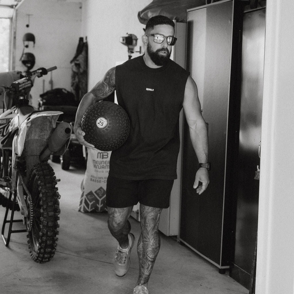 Athlete carrying a Gorila Fat Slam Ball in a garage gym, showcasing the strength and durability of Gorila Slam Balls for functional training and free weight workouts.