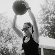 Female athlete performing HIIT, powerful overhead slams with the Gorila Fat Slam Ball in a functional gym setting, demonstrating impact resistance and stable rebound control