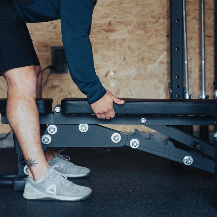 Athlete adjusting seat height on the Gorila Fitness adjustable bench, precision laser-cut steel frame built in Canada