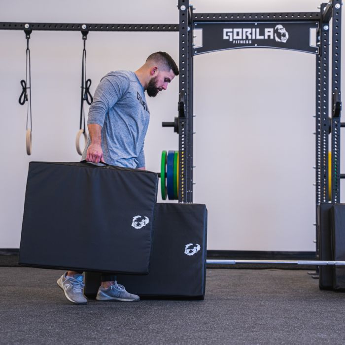Athlete carrying Gorila Fitness Regular size drop pads with reinforced handles, portable design for strength and weightlifting setups, made in Canada