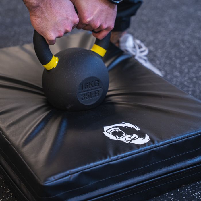Close-up of kettlebell impact test on Gorila Fitness drop pad showing superior shock absorption and durable surface construction