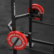 Gorila Open Hex Bar 2.0 mounted on a power rack with red Gorila Fitness 55 lb bumper plates, showing the open-frame design, rackable structure, and integrated deadlift jack for efficient loading and training.