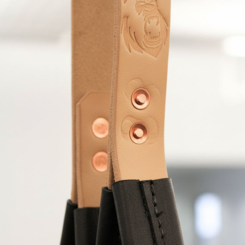 Pair of Gorila tricep leather straps hanging from cable attachment, ideal for strength and bodybuilding accessory work.