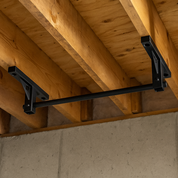 Gorila wall-mounted pull-up bar securely installed on trusses between two wooden ceiling beams in a home basement gym.