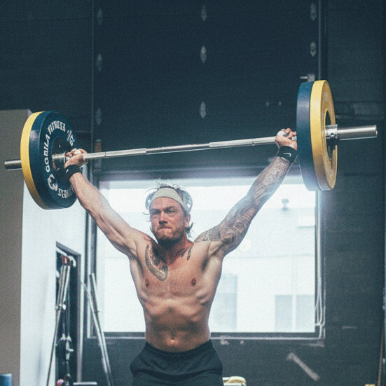 Person lifting a barbell with Gorilla Fitness weights in a gym setting